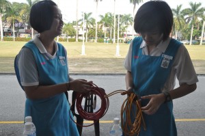 Dua orang pengawas pusat sumber sedang menggulung wayar sebelum Saringan Hari Sukan bermula.