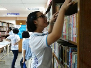 Pengawas perpustakaan sedang mengemaskan rak buku.